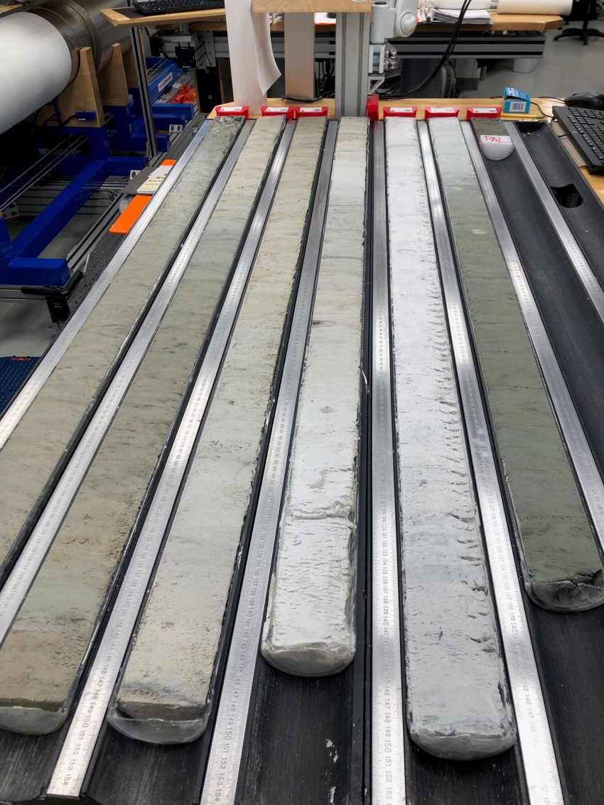 Photograph of 6 long drill core samples in varying shades of grey