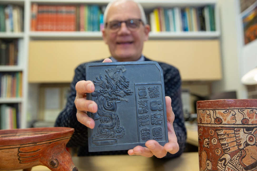 professor holds ancient mayan sculpture